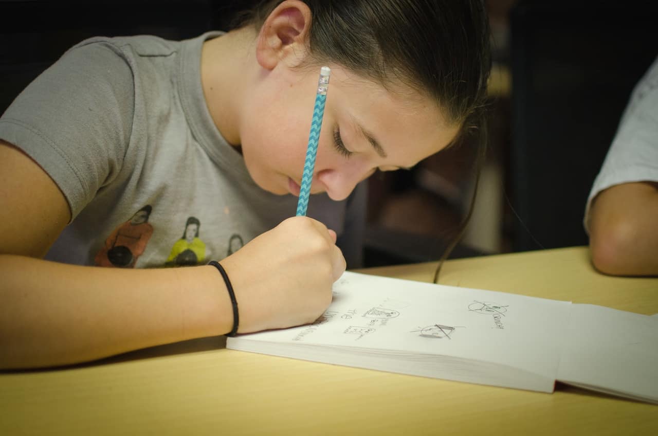 Student drawing with pencil in notepad